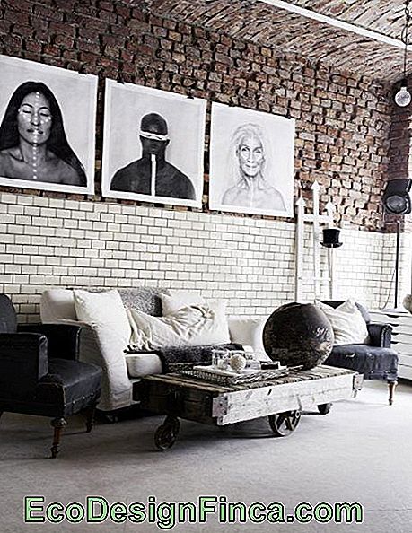 Bilde av et loft med industriell dekorasjon. Foran sofaen er et firkantet salongbord med hjul og laget av tre.