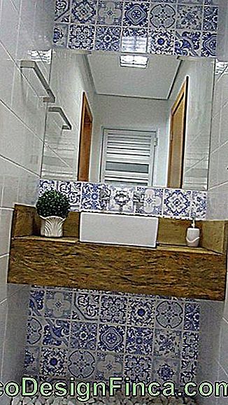 Medinis stalviršis su tualetu su veidrodžiu priešais aukštą sieną, padengtą Portugalijos plytelėmis.