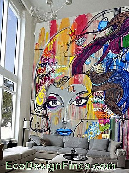 Photo d'une pièce avec des murs très hauts. Sur le mur derrière le canapé se trouve un graphite coloré avec le visage d’une femme.