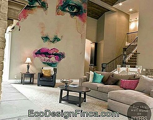 Grand salon avec meubles espacés. Sur un mur latéral se trouvent les graffitis sur le visage d’une femme aux couleurs vives.