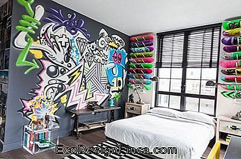 Image d'une pièce avec le mur derrière le lit orné de différentes formes de skateboard. Le mur à côté du lit a un graphite avec plusieurs conceptions différentes.