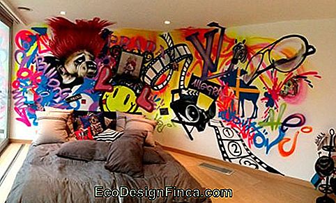 Image d'une chambre avec le mur derrière le lit décoré de graphite. Dans les dessins, on peut voir des pellicules, des lunettes, des emoji et un bouledogue.