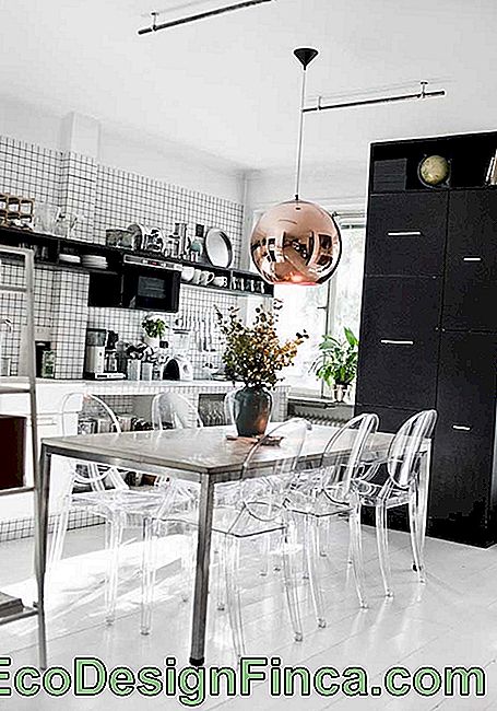 Køkken og spiseplads integreret med højdepunkt til rustfrit bord ledsaget af transparente akryl stole