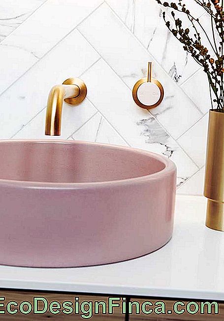 Žavingas ir subtilus vonios kambarys su rožine vonia ir auksiniu maišytuvu